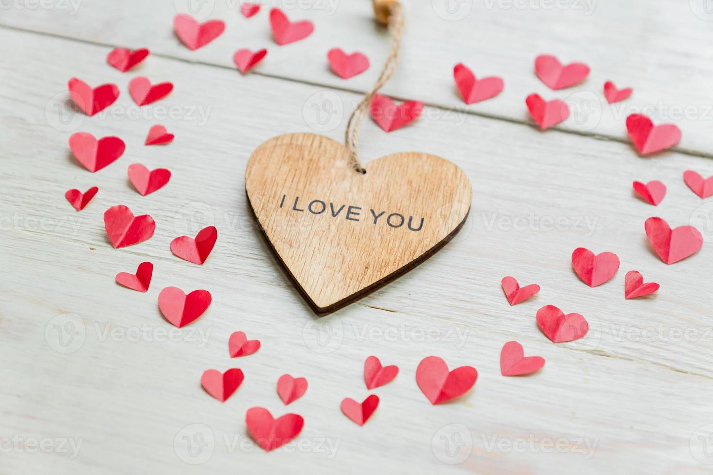 Big red heart made of cut out paper small hearts and wooden heart with I love you inscription on wooden backround. Handmade decoration for Valentine's day. photo