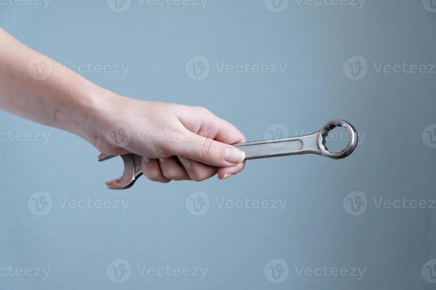 woman holding a wrench in her hand on gray background. photo