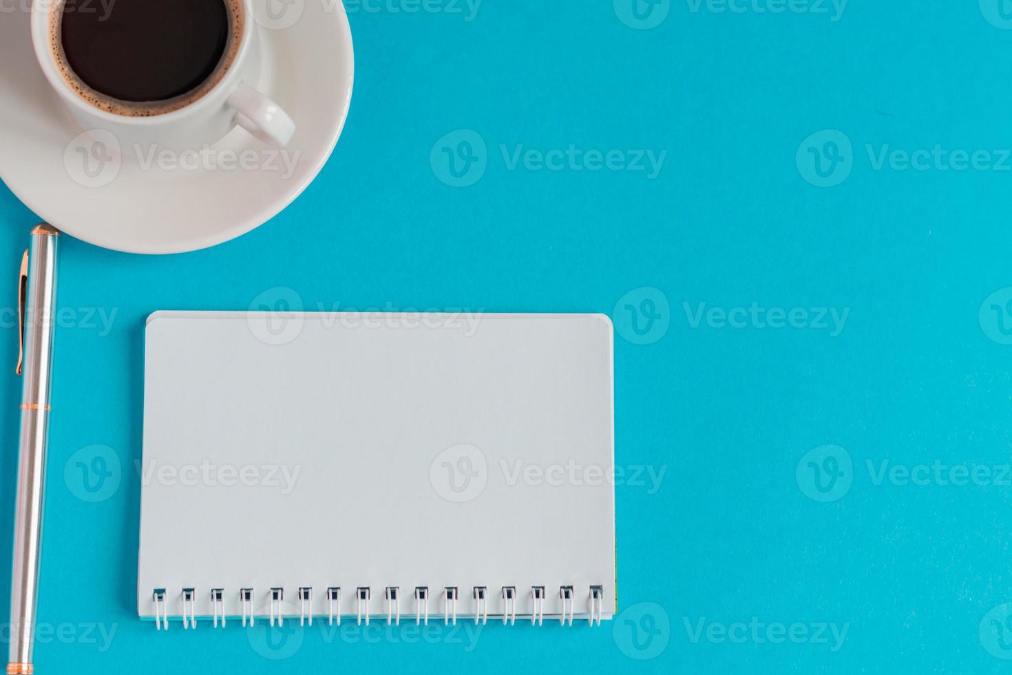 cup of black coffee with notebook and pen on light blue background. business concept with copy space photo