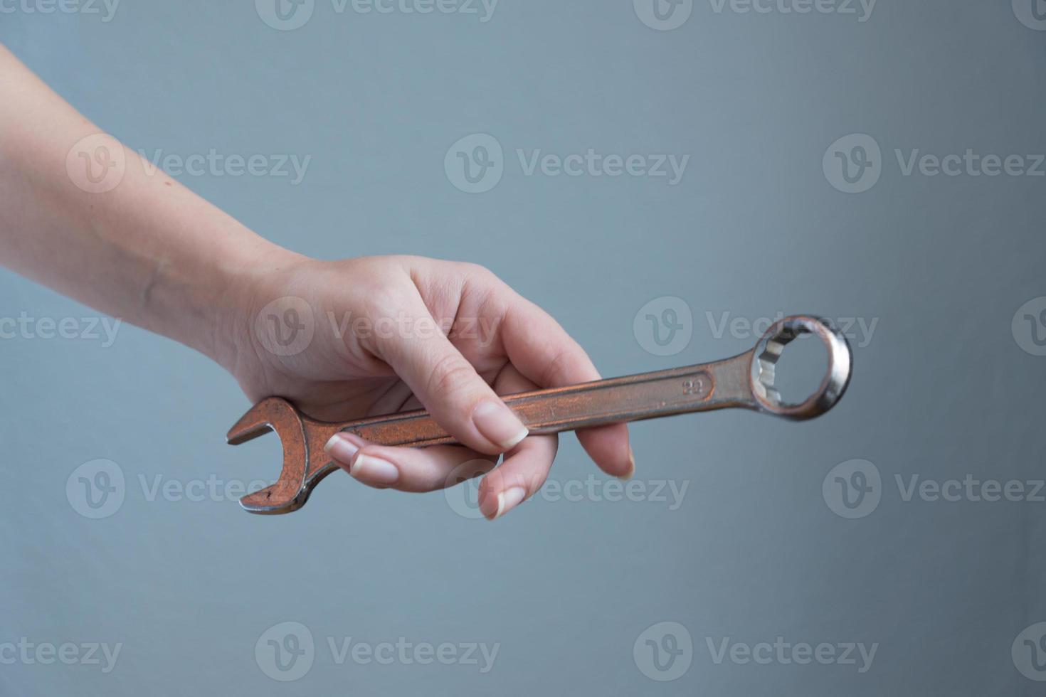 woman holding a wrench in her hand on gray background. photo