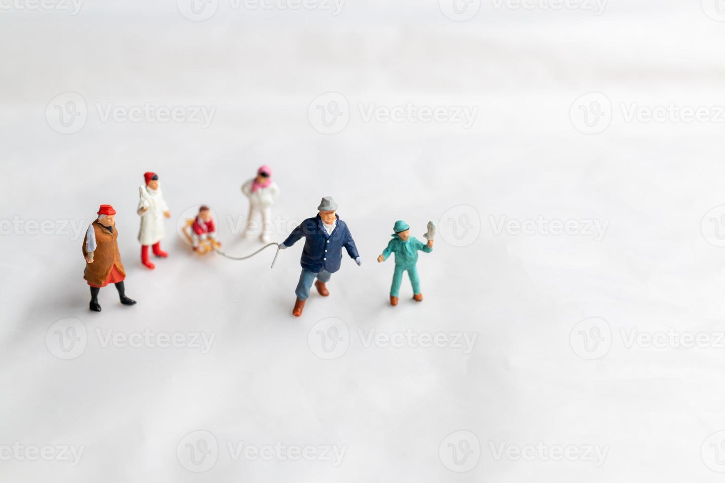 Miniature people Happy family ride a sleigh with snow background photo