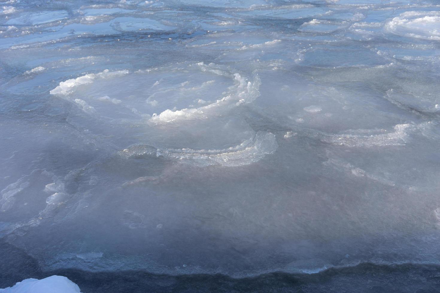 Icy water surface with cracks and ice floes photo