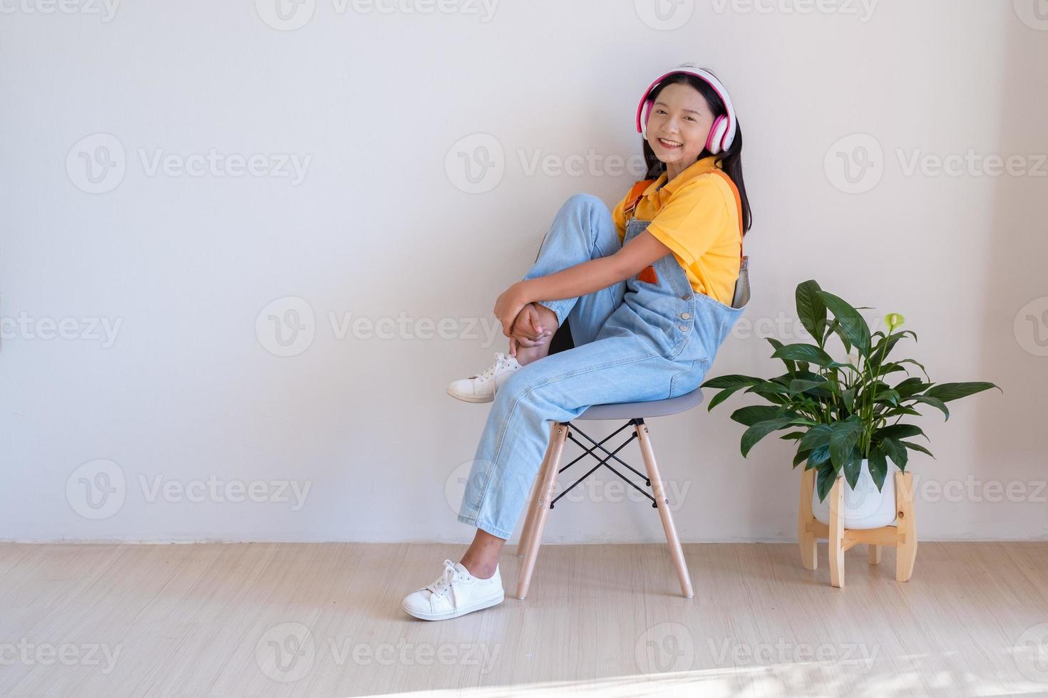 The happy girl sitting on a chair listening to music in minimal room at home. photo