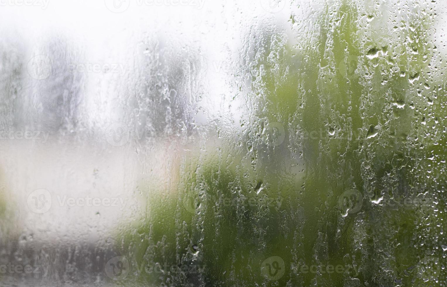 Lluvia Pesada. gotas de lluvia en el cristal de la ventana en un día de verano. enfoque selectivo, poca profundidad de campo. gotas de agua caen sobre una ventana mojada. vaso lleno de gotas durante un aguacero. foto