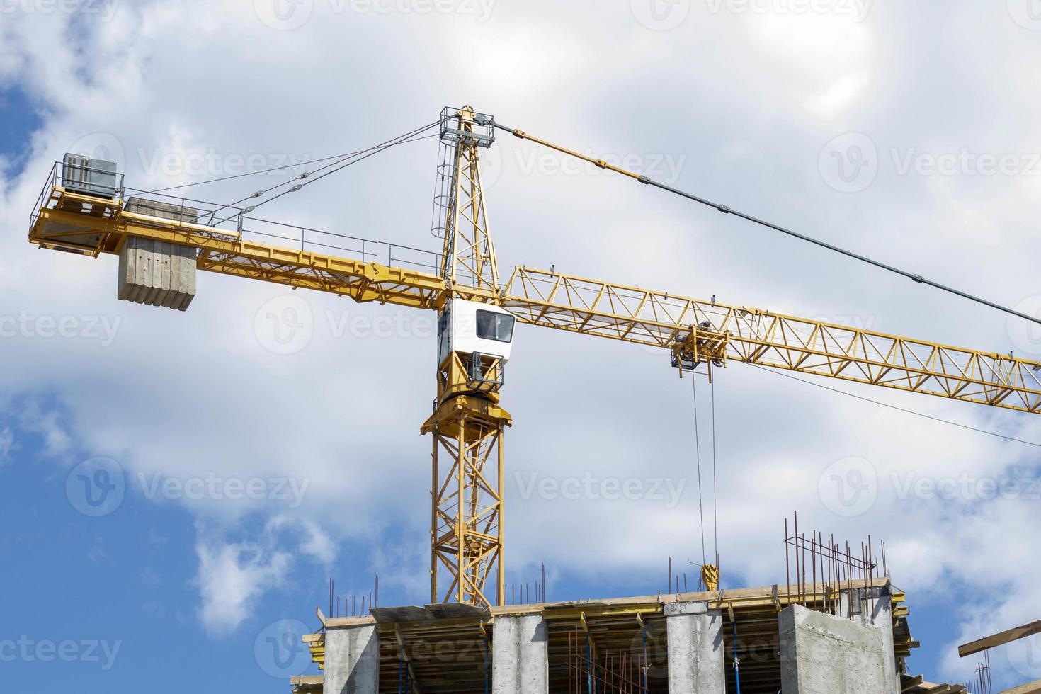 A working construction tower crane against a cloudy sky on a sunny day. The concept of urban development and construction. Industrial background. Crane engineering, construction industry tool. photo