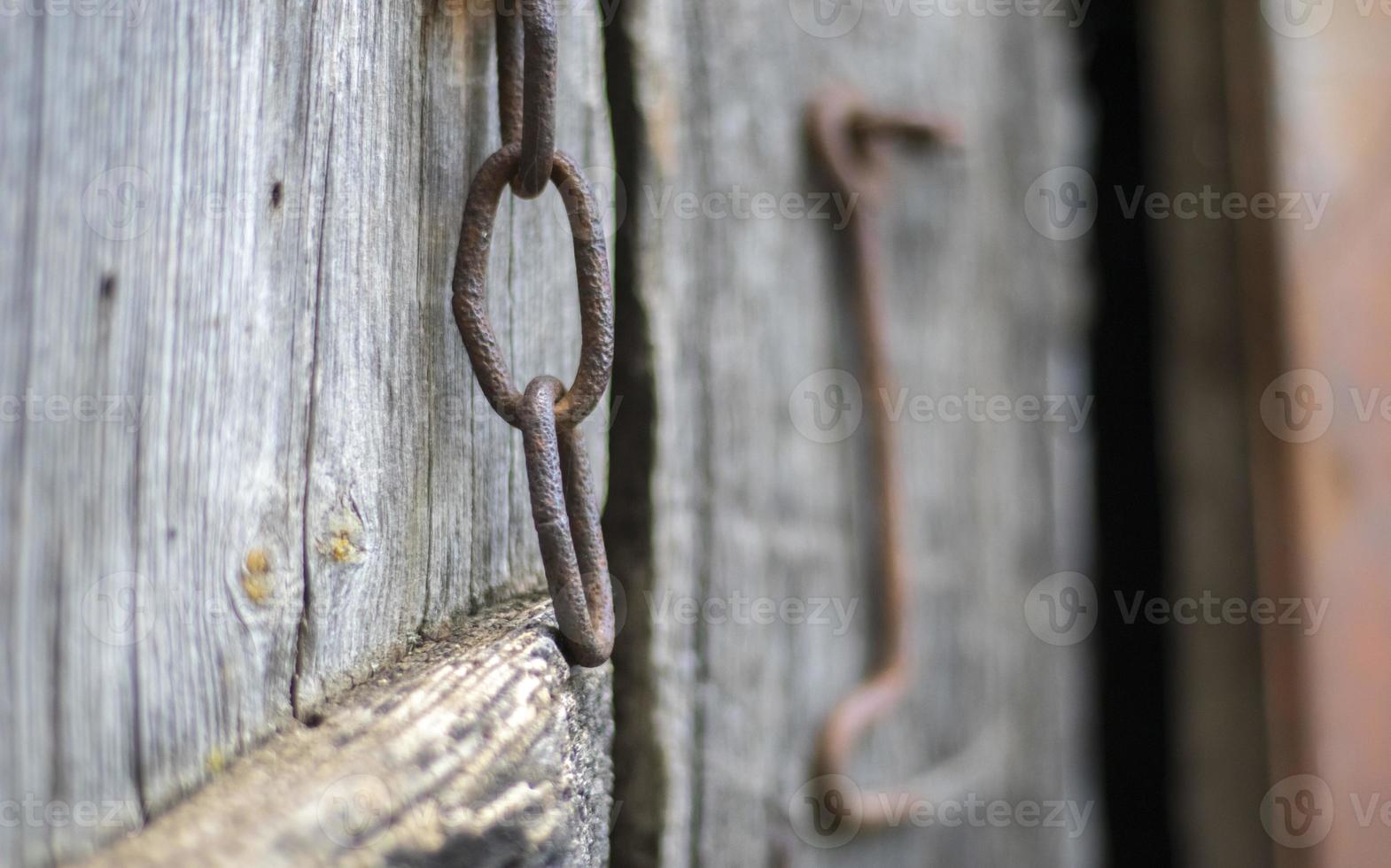 Isolated old rusty door latch on a wooden door. Close-up. Problematic weathered panels. Old wall texture background. Detail of an old wooden door with a rusty door latch. photo