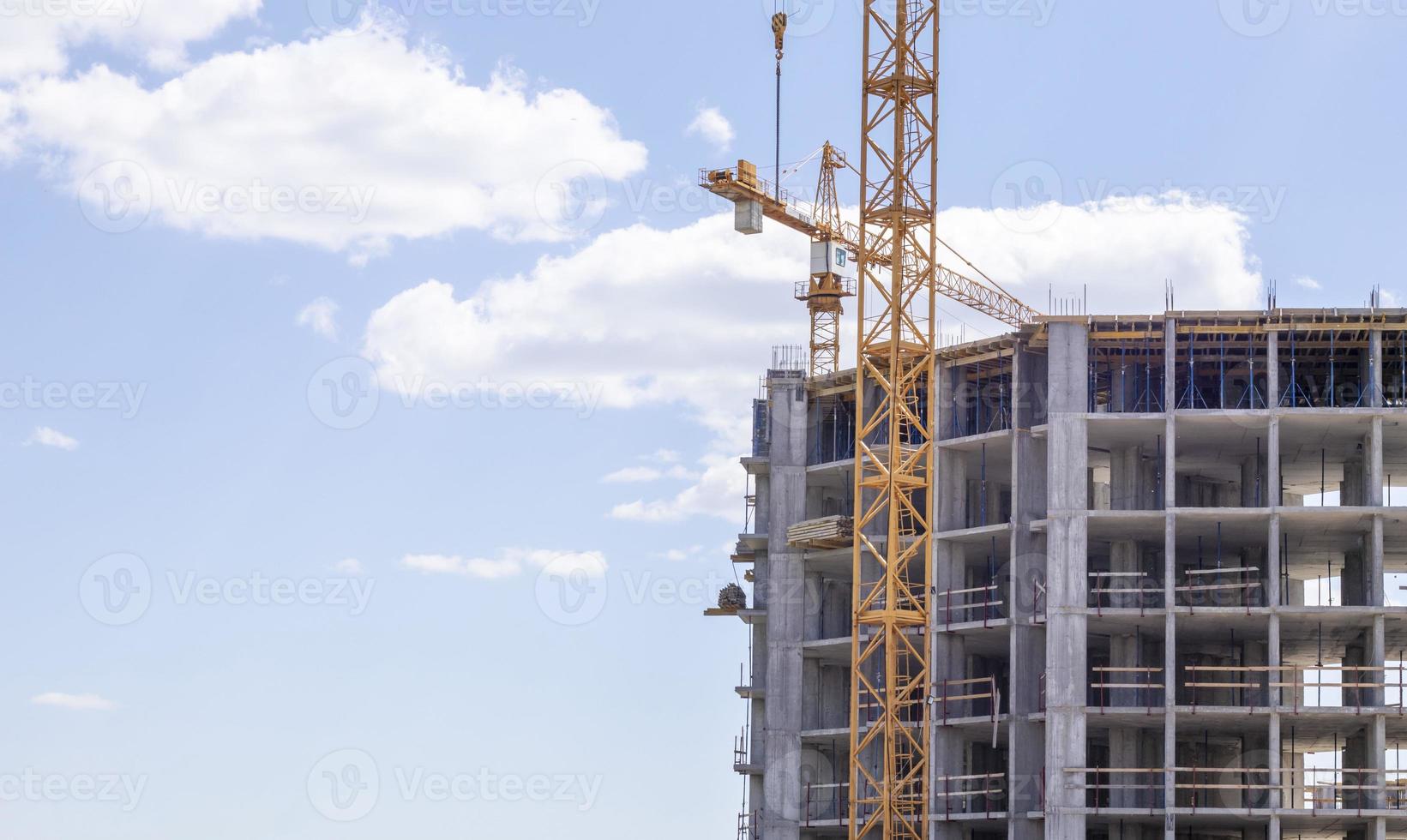 A working construction tower crane against a cloudy sky on a sunny day. The concept of urban development and construction. Industrial background. Crane engineering, construction industry tool. photo