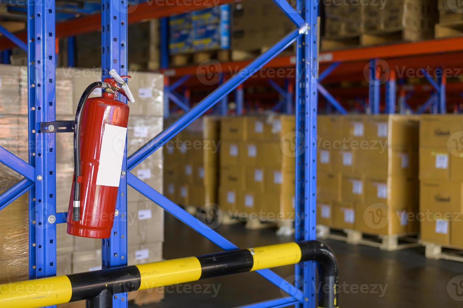 Fire extinguisher on shelf of cardboard boxes in modern warehouse. photo