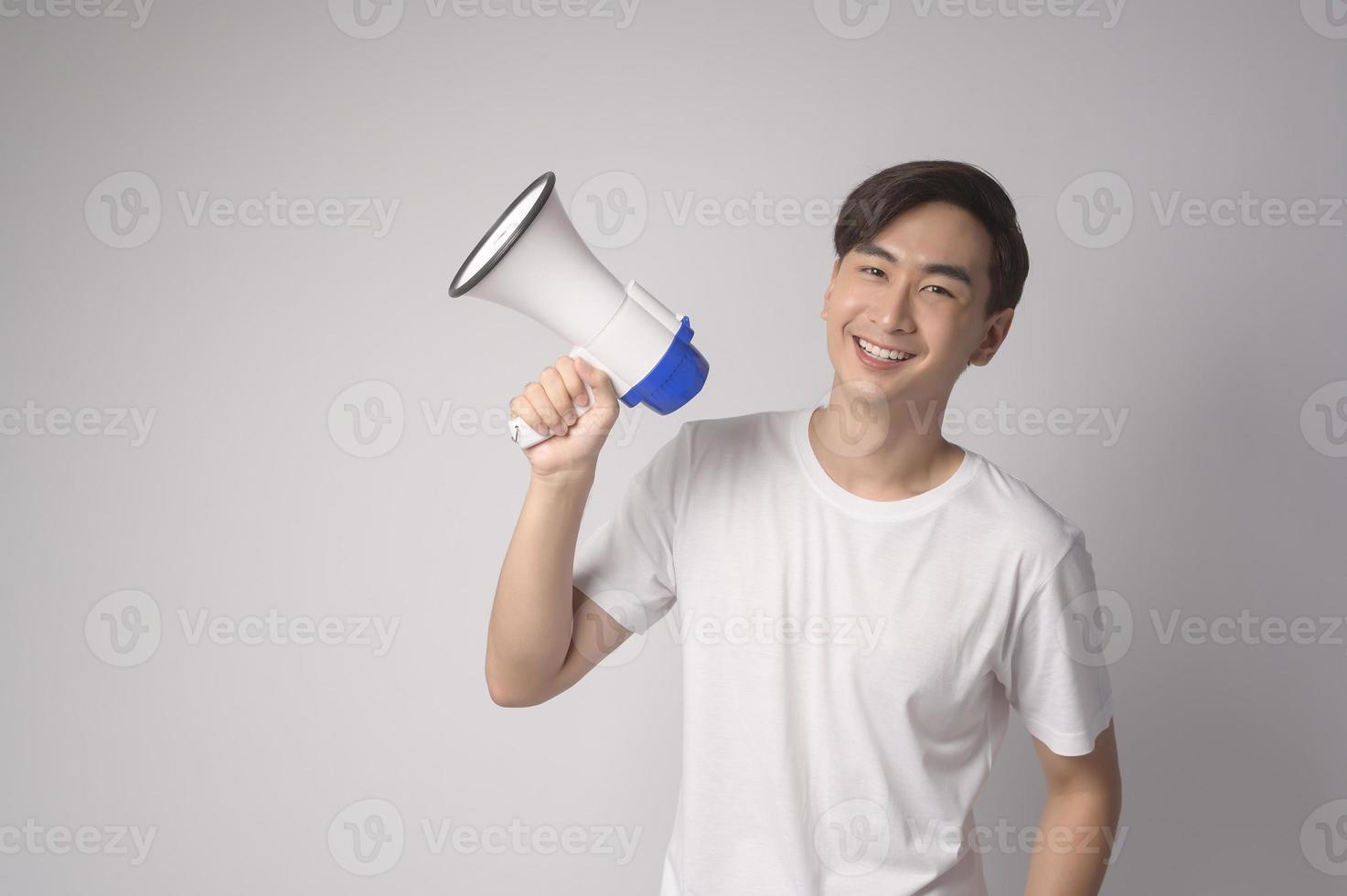 Young smiling man holding megaphone over white background studio. photo