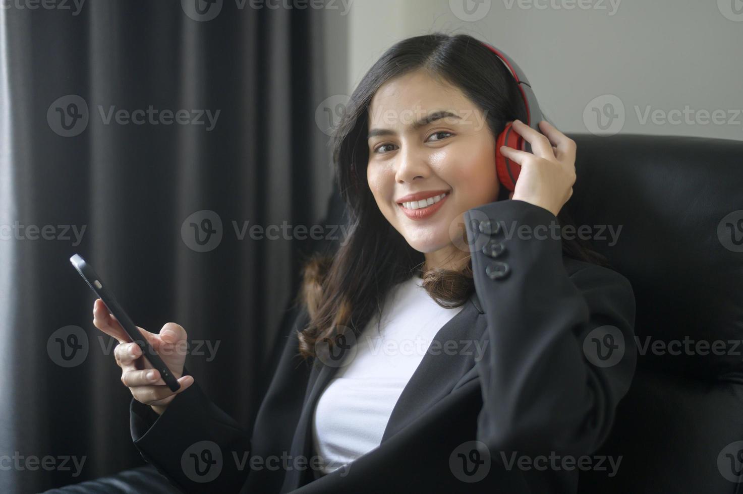 joven mujer de negocios relajante usando teléfono inteligente y escuchando música en la oficina moderna. foto