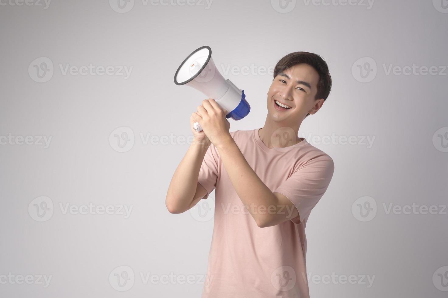 Young smiling man holding megaphone over white background studio. photo