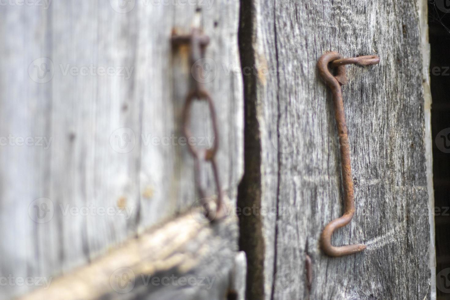 Isolated old rusty door latch on a wooden door. Close-up. Problematic weathered panels. Old wall texture background. Detail of an old wooden door with a rusty door latch. photo