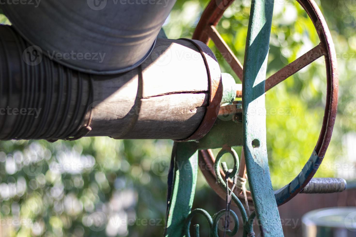 A well with a bucket in a European village. Sunny day. Metal bucket for a water well. Detail of a well with a tin bucket in the countryside. Decorating the garden with vintage items. photo