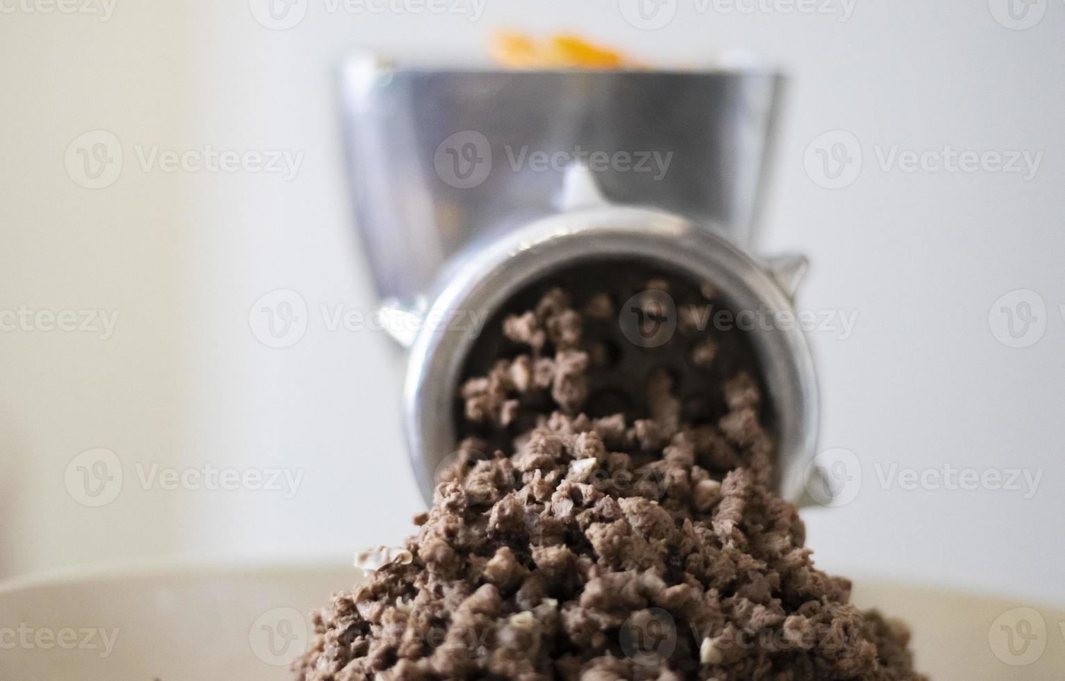Minced meat in a manual mechanical meat grinder. Fresh boiled meat is ground with an old metal meat grinder, close-up in the kitchen. photo