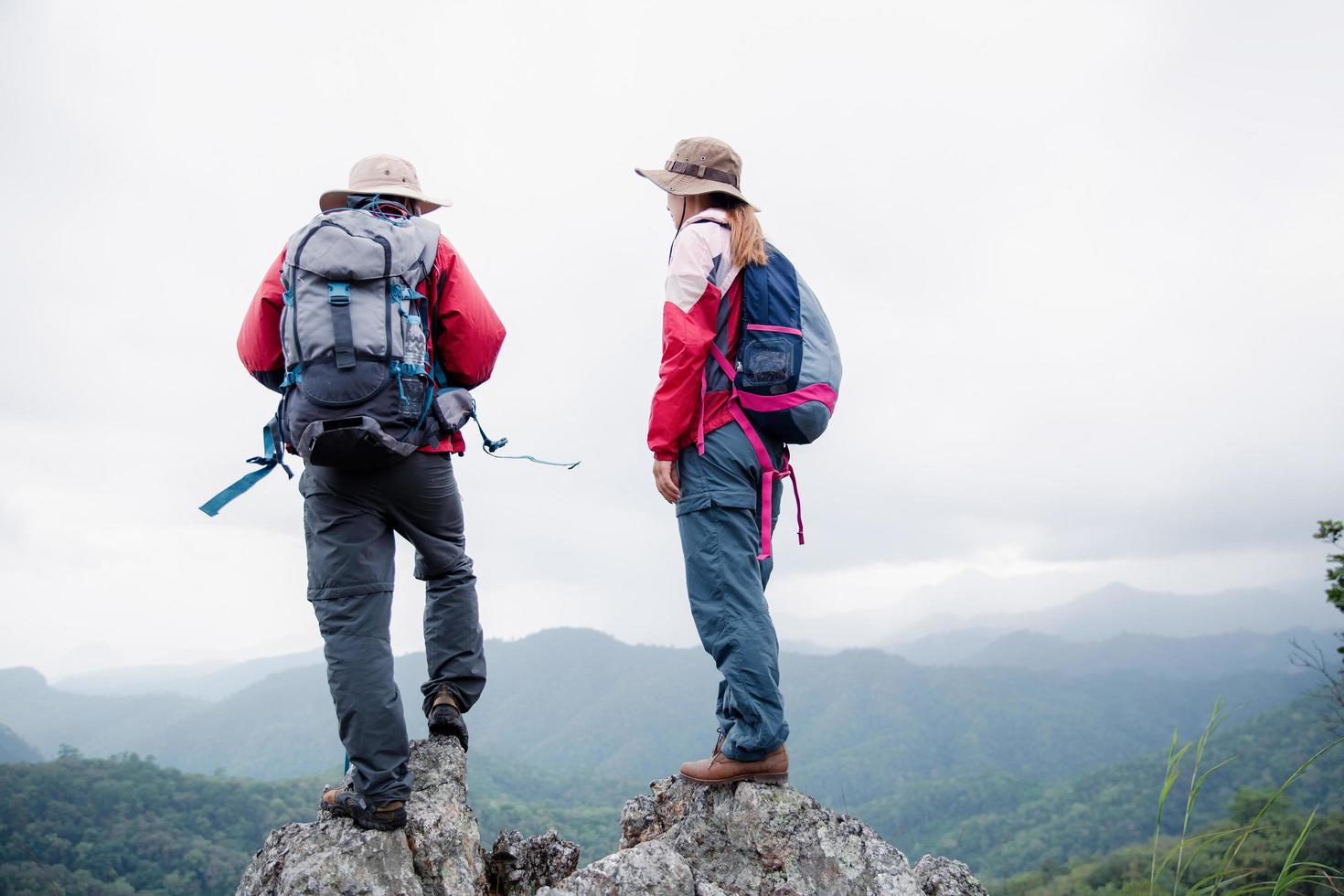 Young tourist couple watching spectacular mountain scenery in high mountains. man and woman hiker on top rock. A couple of travelers in love. People greet the dawn. Lovers travel. Copy space photo