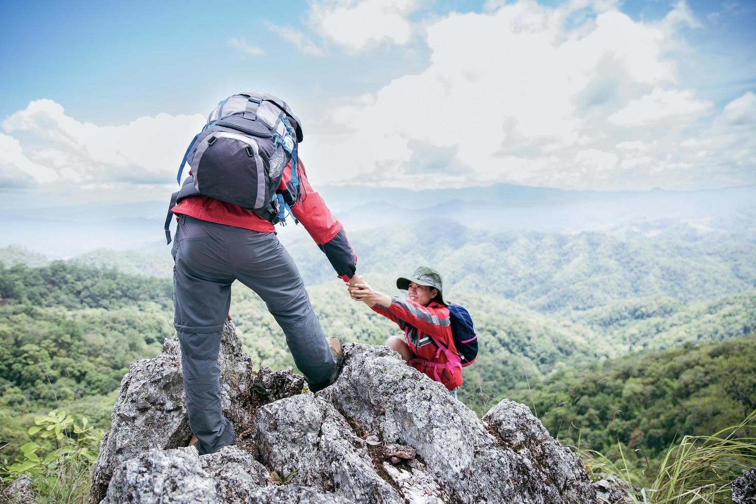 Person hike friends helping each other up a mountain. Man and woman giving a helping hand and active fit lifestyle. Asia couple hiking help each other. concept of friendship, teamwork. photo