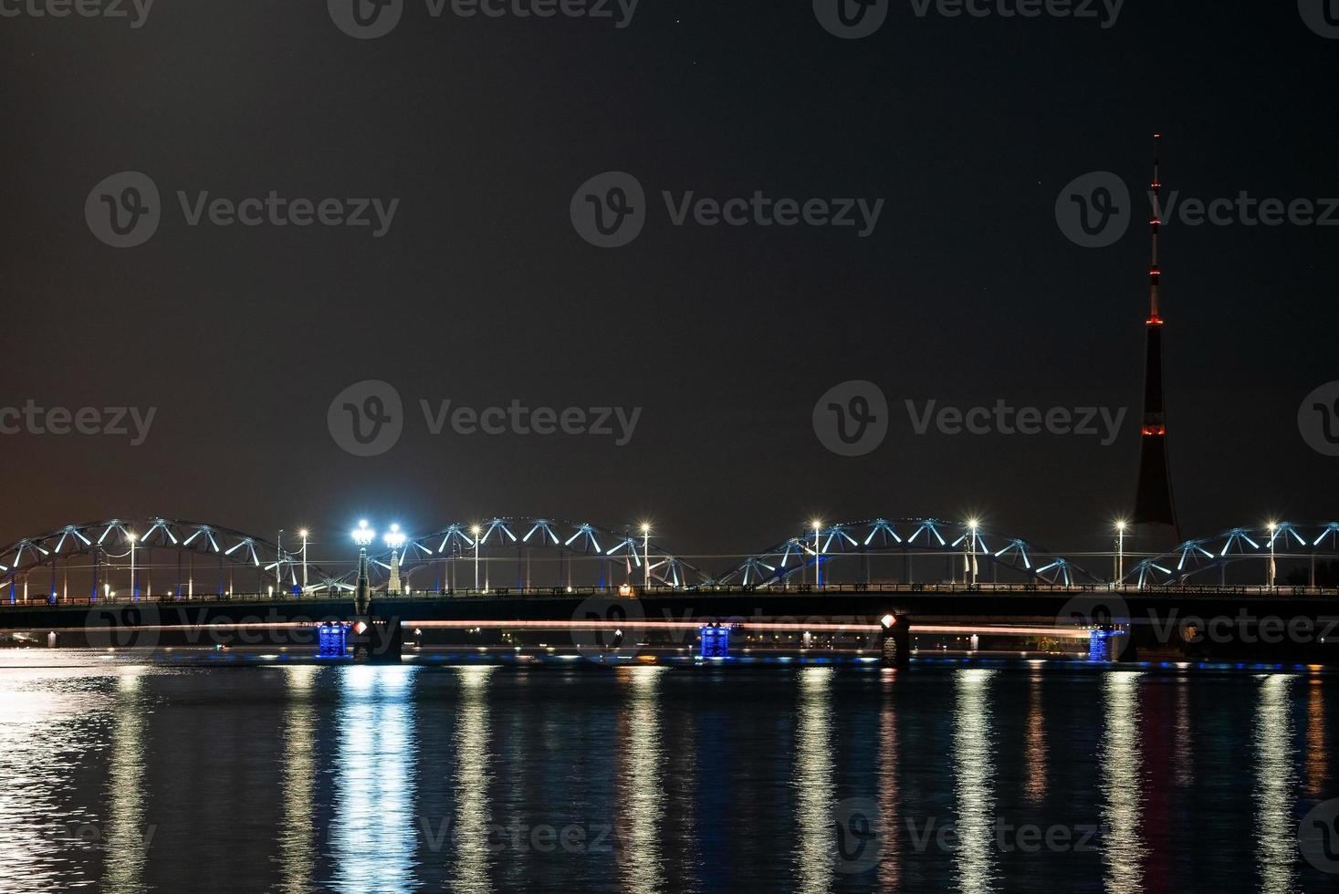 vista nocturna del puente ferroviario en riga sobre el río daugava. foto