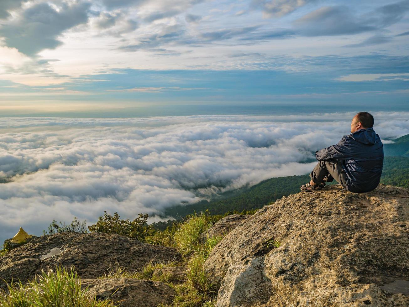 Asian men Sit on the cliff with beautiful sunrise sky on Khao Luang mountain in Ramkhamhaeng National Park,Sukhothai province Thailand photo