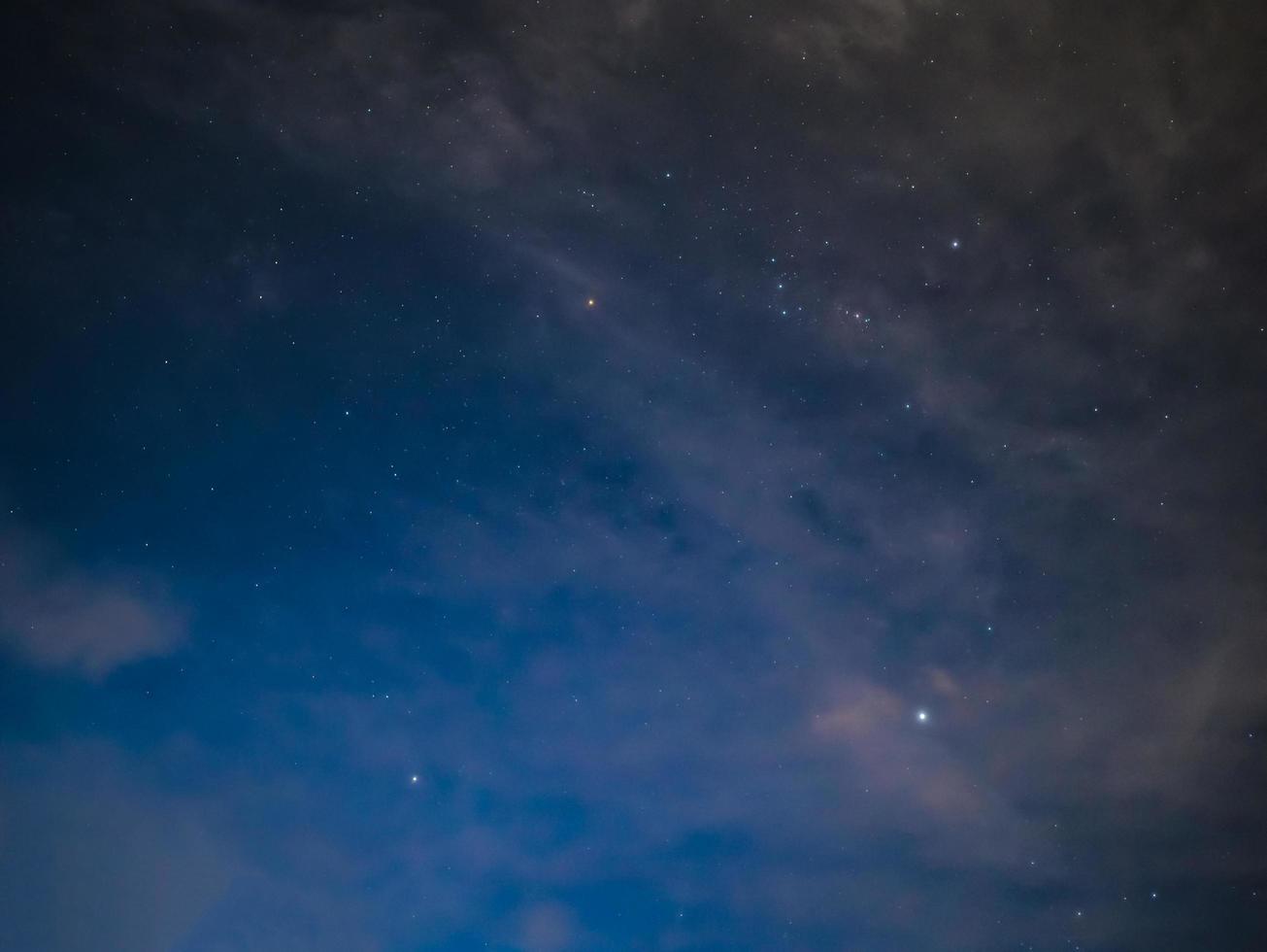 cielo nocturno con estrellas y nubes blancas en la montaña foto