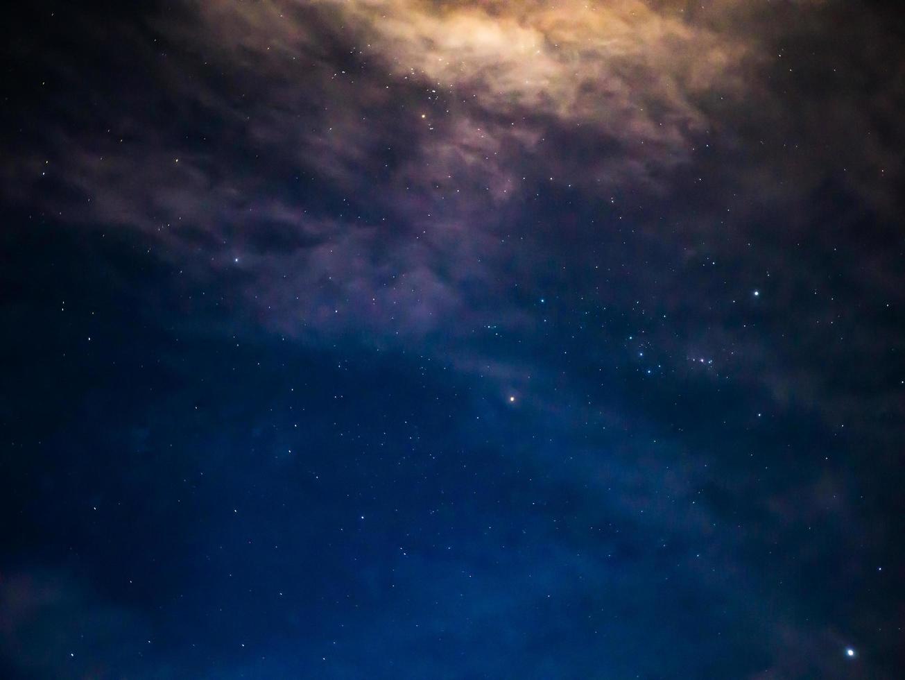 cielo nocturno con estrellas y nubes blancas en la montaña foto