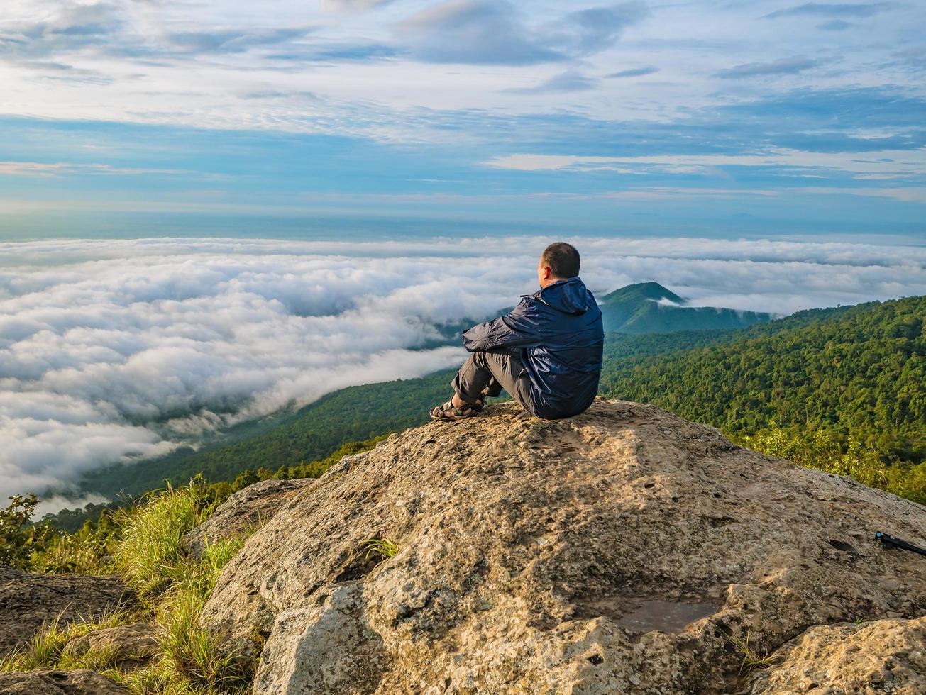 Asian men Sit on the cliff with beautiful sunrise sky on Khao Luang mountain in Ramkhamhaeng National Park,Sukhothai province Thailand photo