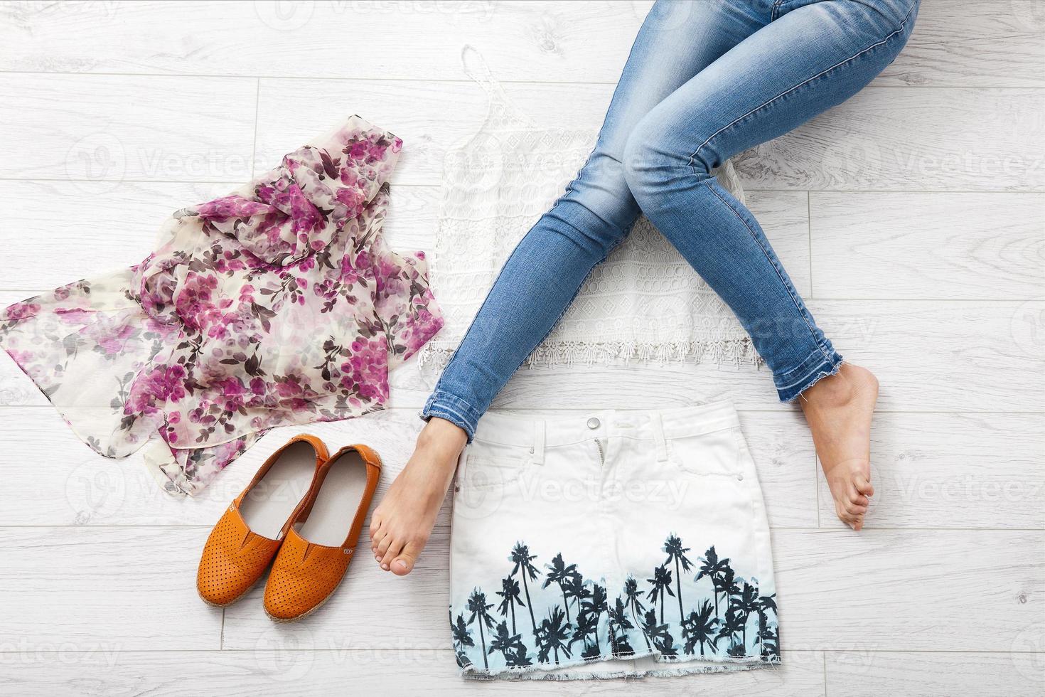 Stylish outfit with accessories and female legs on white wooden background. Top view and copy space photo