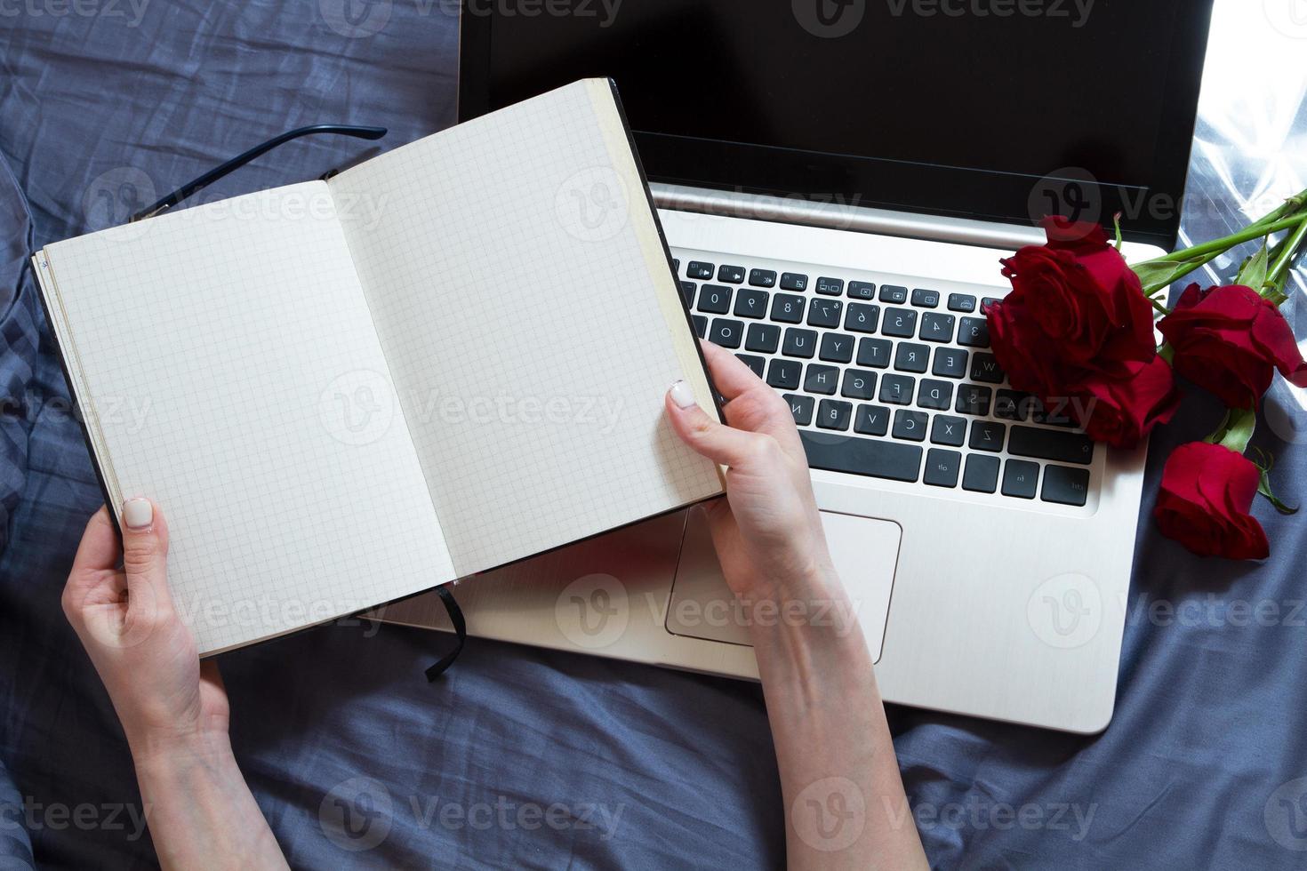 Hands, computer keyboard, bed top view. Workplace background, work at home, notepad and flowers photo
