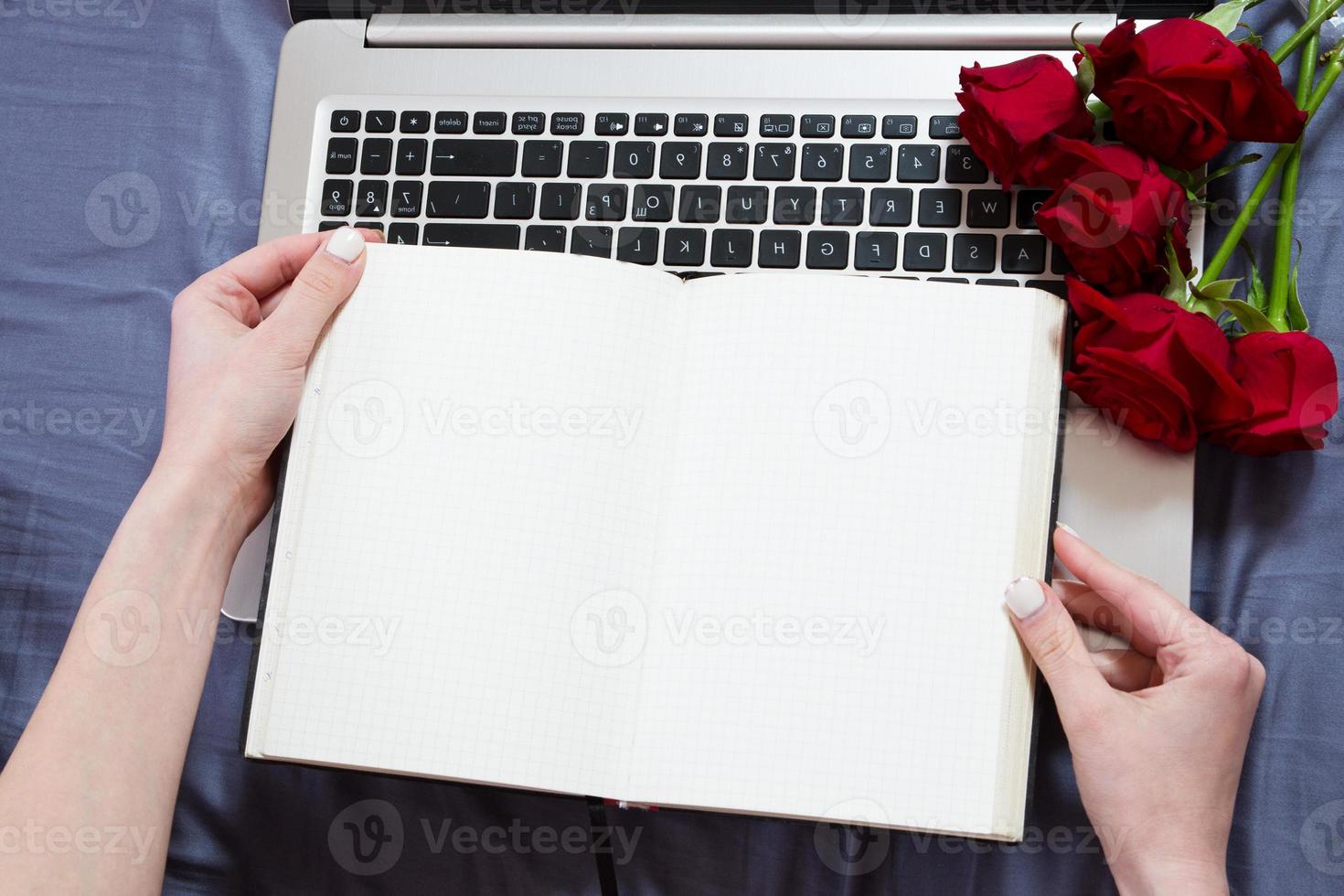 Hands, computer keyboard, bed top view. Workplace background, work at home, notepad and flowers photo
