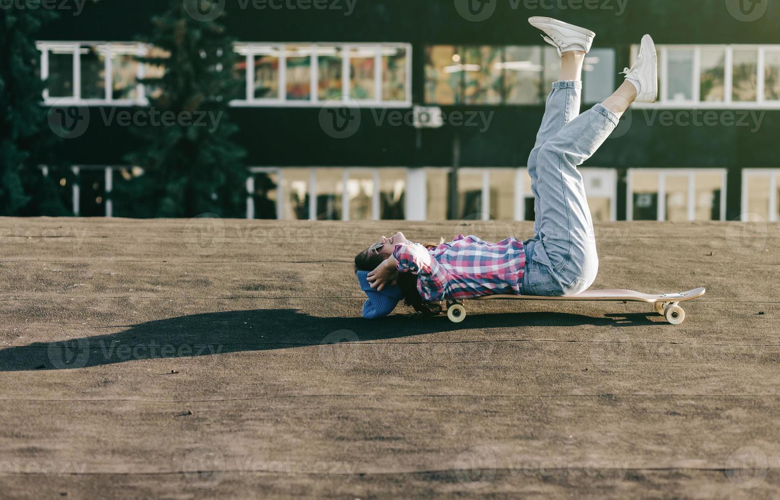 teenage girl in a hat lies on a longboard photo