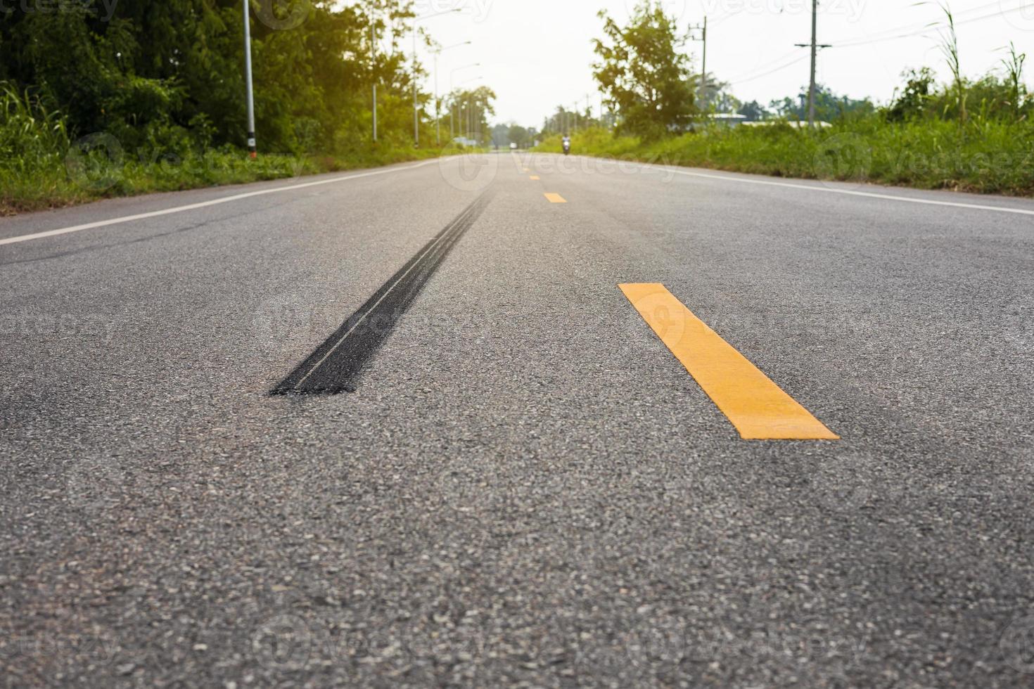 A close-up low-angle view. A long line of black rubber tires stopping violently against the paved road surface. photo