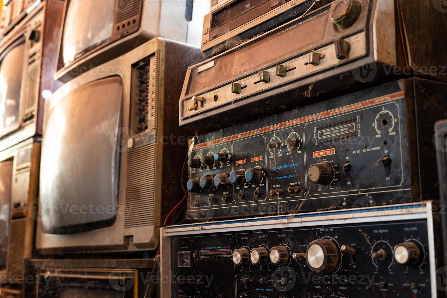 Old and dirty stereo amplifiers and black-and-white televisions are stacked. photo