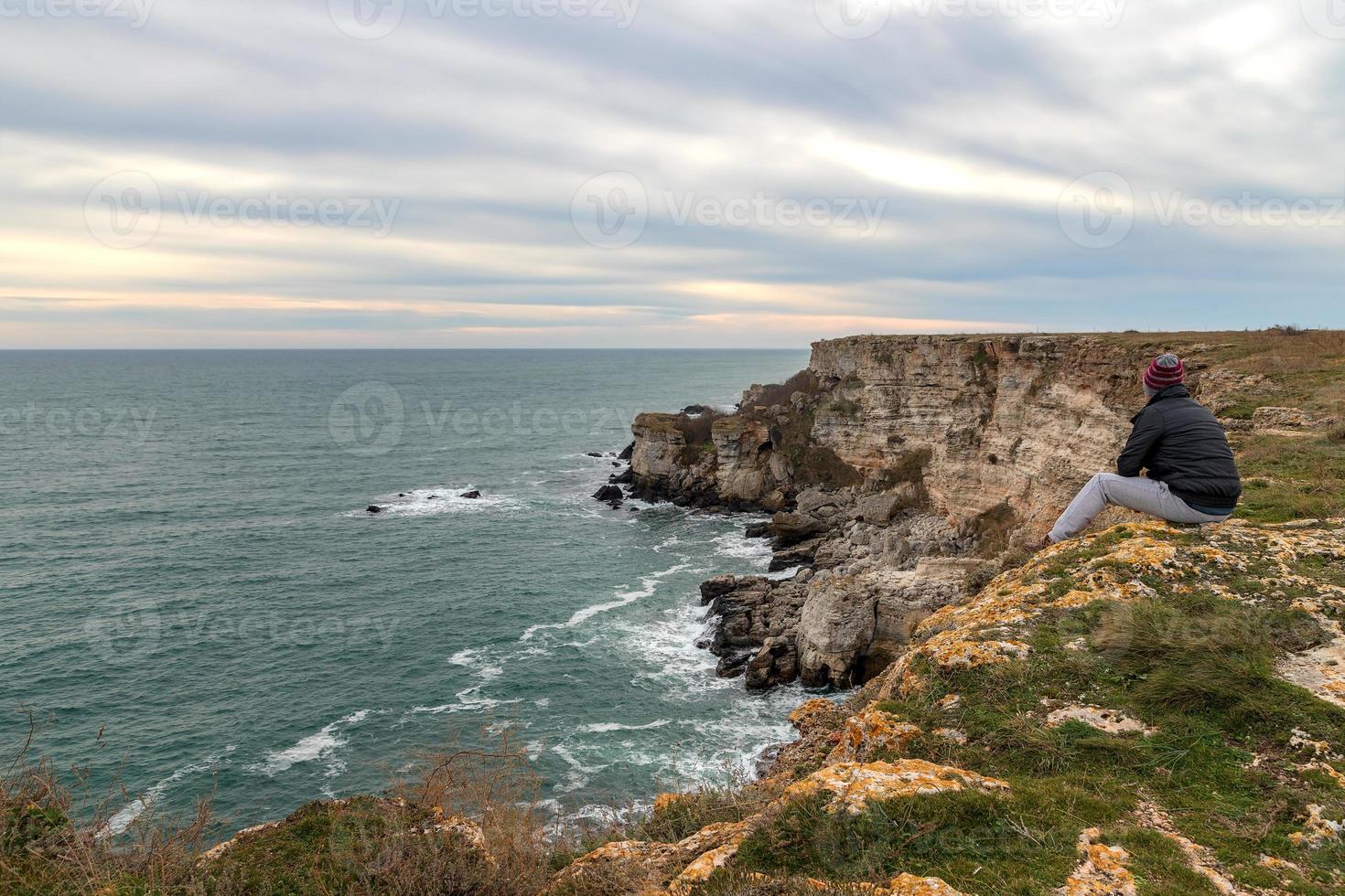 A man enjoys a beautiful sea view from the top of a cliff. photo