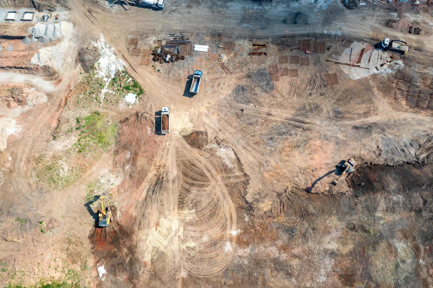Aerial top view of excavators and dump trucks working at the construction site photo