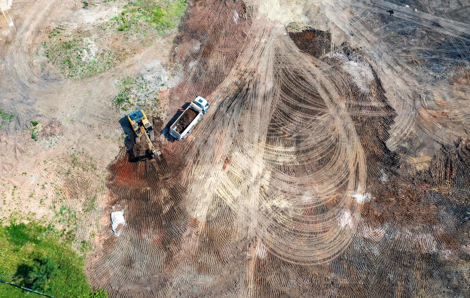 Aerial top view of excavator and dump trucks working at the construction site photo