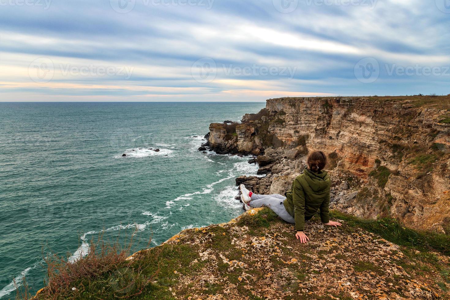 A woman enjoys a beautiful sea view from the top of a cliff. photo