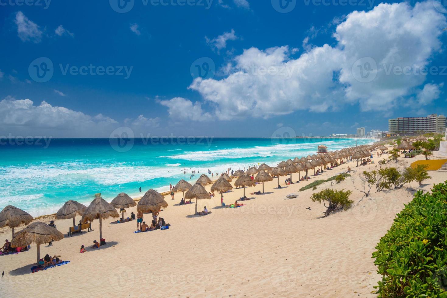 sombrillas en una playa de arena con agua azul en un día soleado cerca de Cancún, México foto