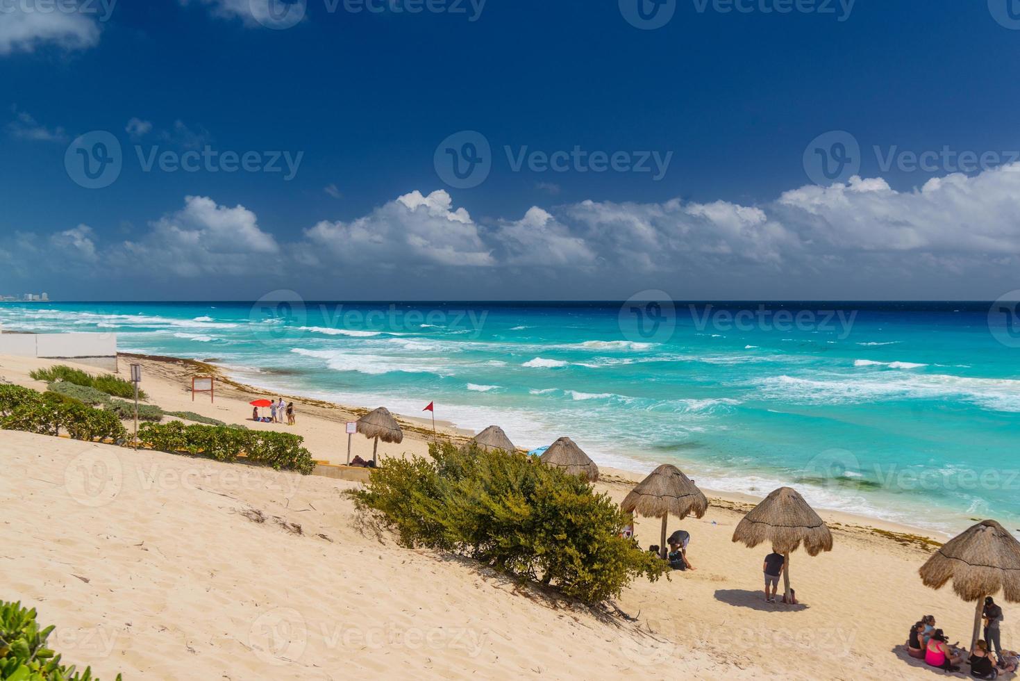 Umbrelas on a sandy beach with azure water on a sunny day near Cancun, Mexico photo