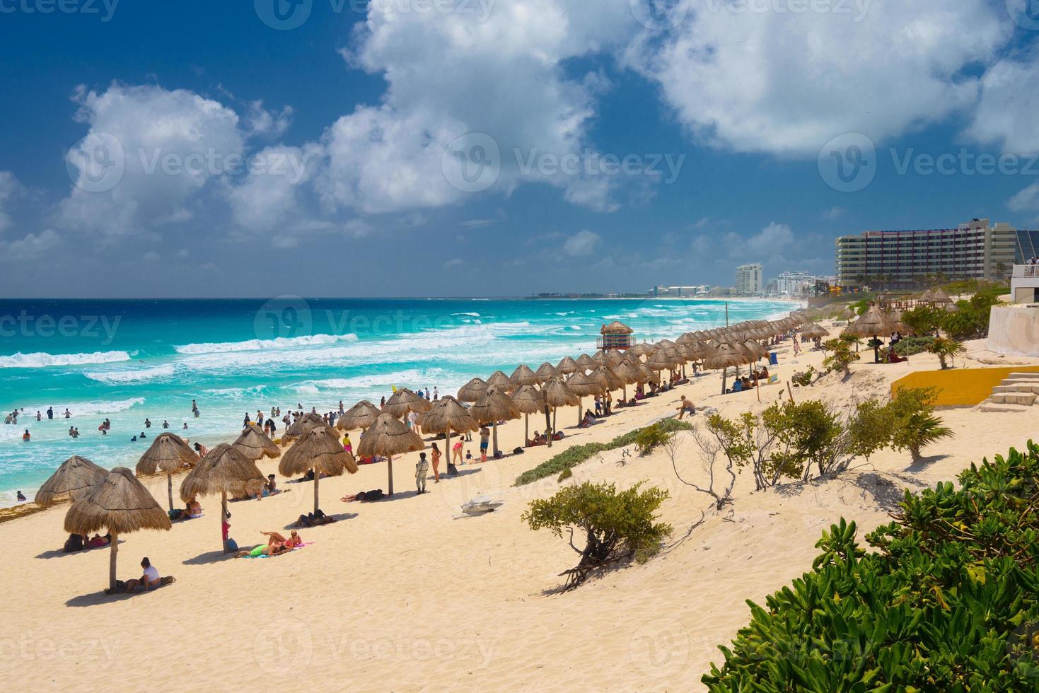 Umbrelas on a sandy beach with azure water on a sunny day near Cancun, Mexico photo