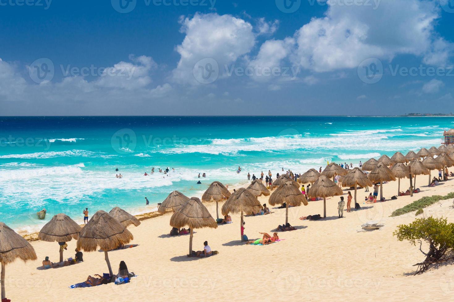 Umbrelas on a sandy beach with azure water on a sunny day near Cancun, Mexico photo