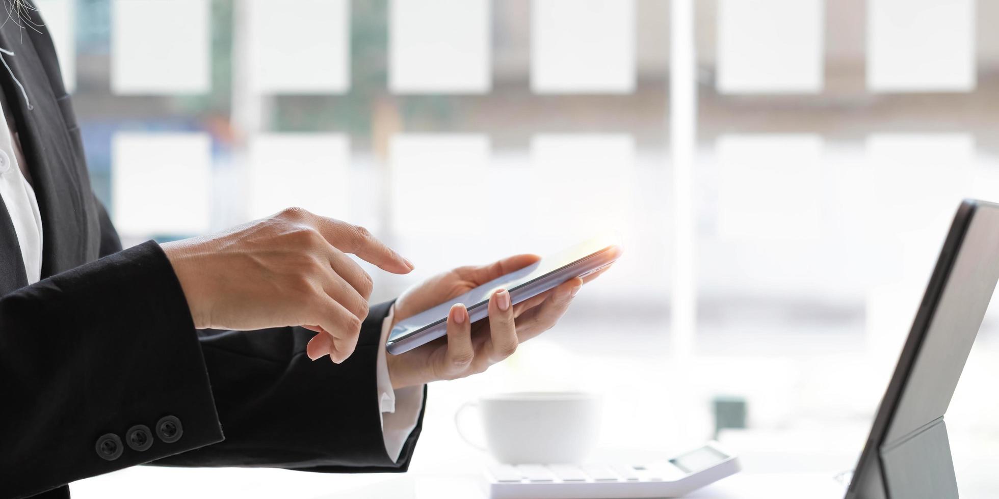 Closeup woman hands using smartphone while sitting at her office desk in modern room. photo