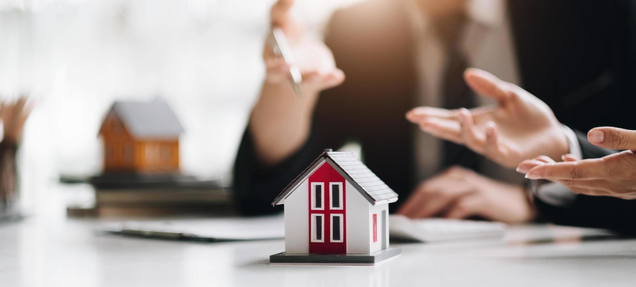Businessman signs contract behind home architectural model photo