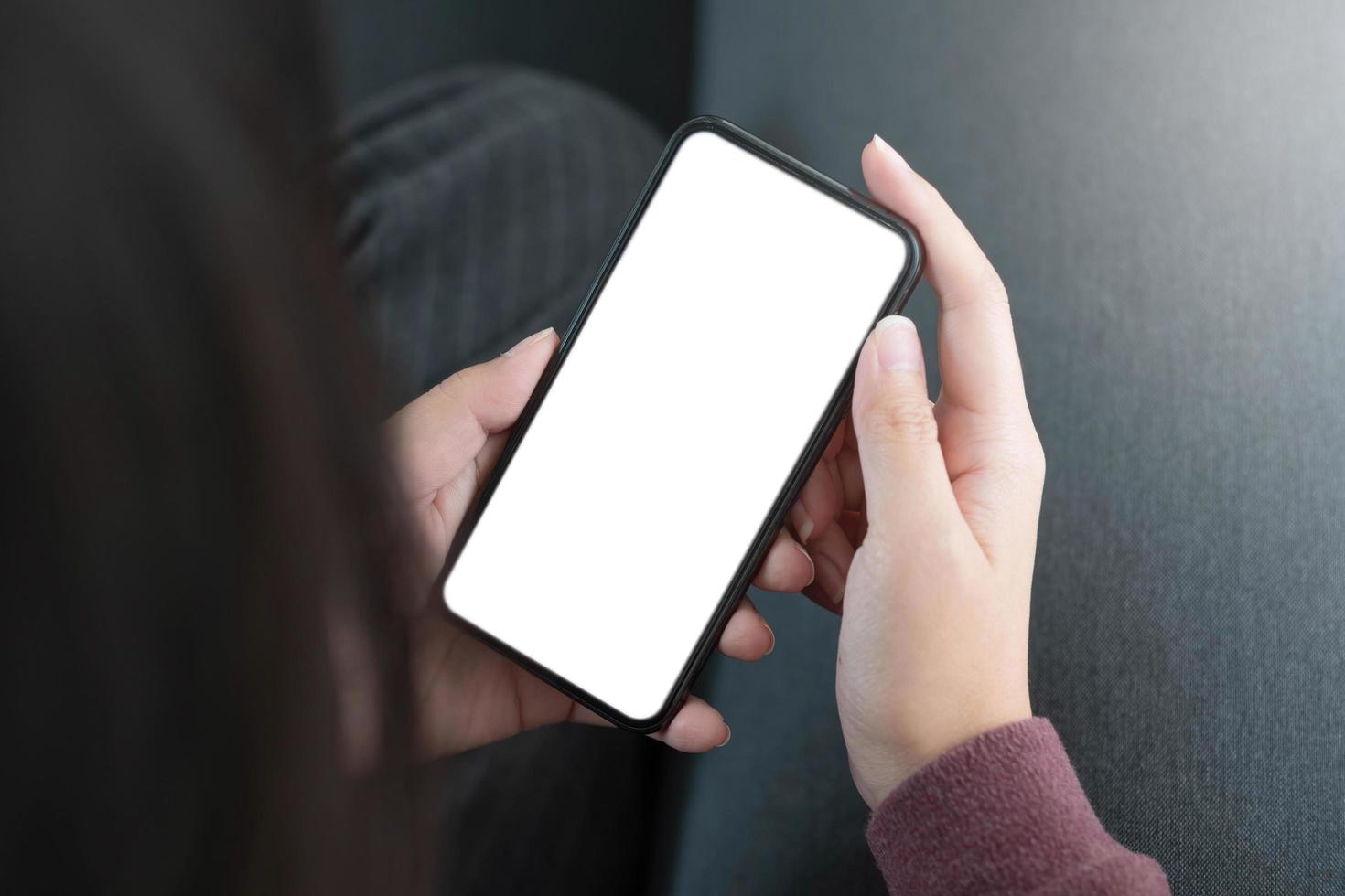 Mockup image blank white screen cell phone.women hand holding texting using mobile on sofa. photo