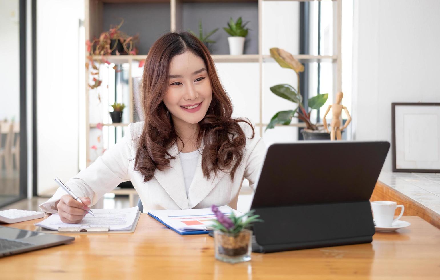 Beautiful Asian businesswoman analyzes charts using laptop calculator at the office. photo