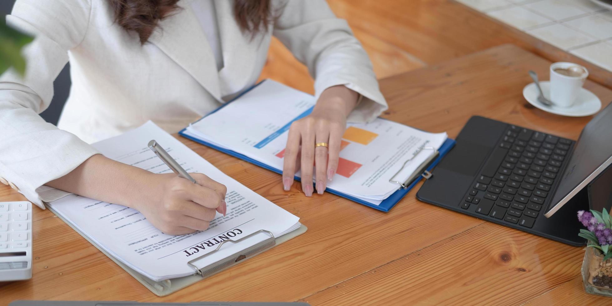 mujer de negocios que usa calculadora y computadora portátil para hacer finanzas matemáticas en un escritorio de madera en la oficina y el fondo de trabajo comercial, impuestos, contabilidad, estadísticas y concepto de investigación analítica foto