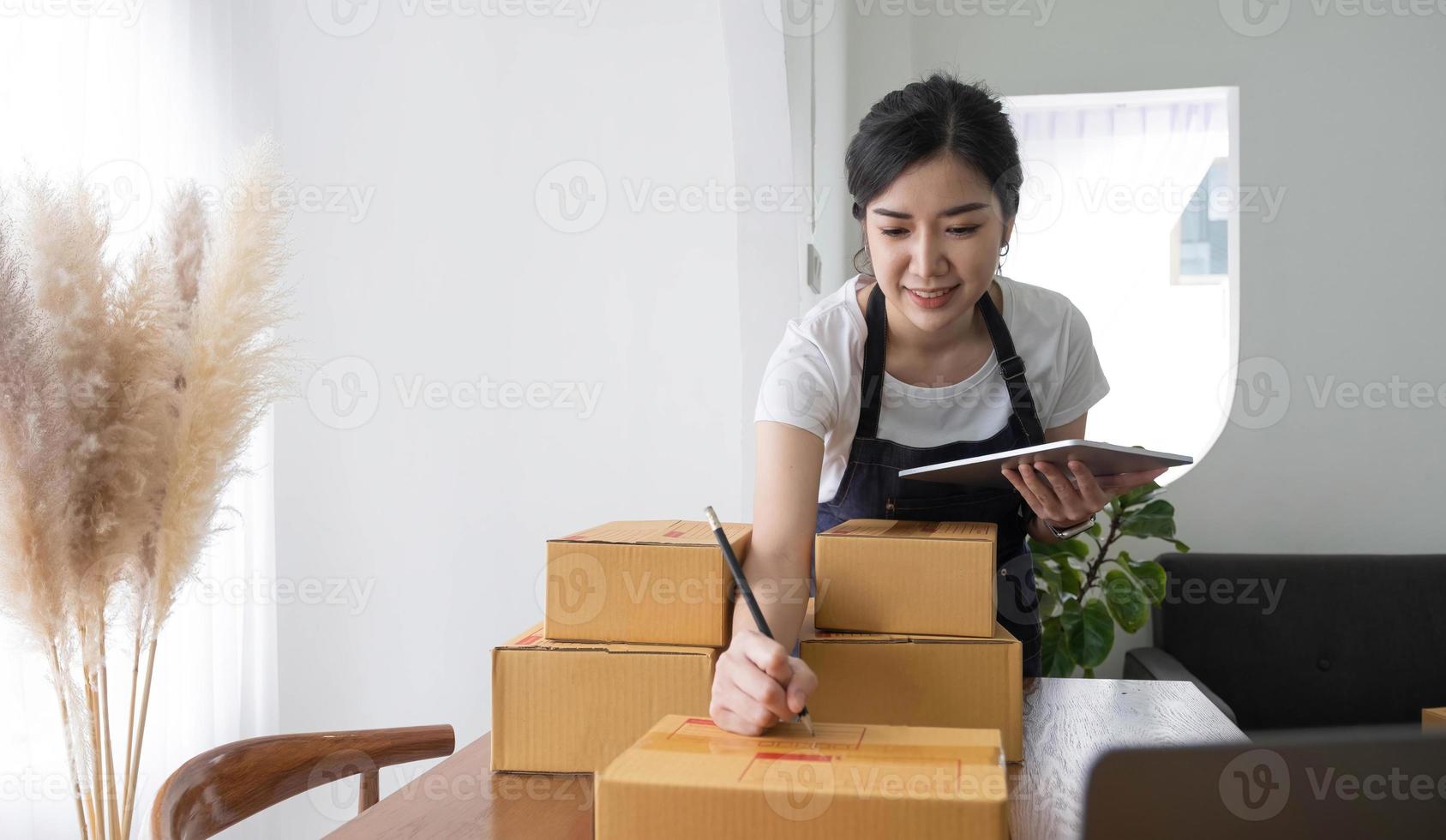 Portrait of Asian young woman SME working with a box at home the workplace.start-up small business owner, small business entrepreneur SME or freelance business online and delivery concept. photo