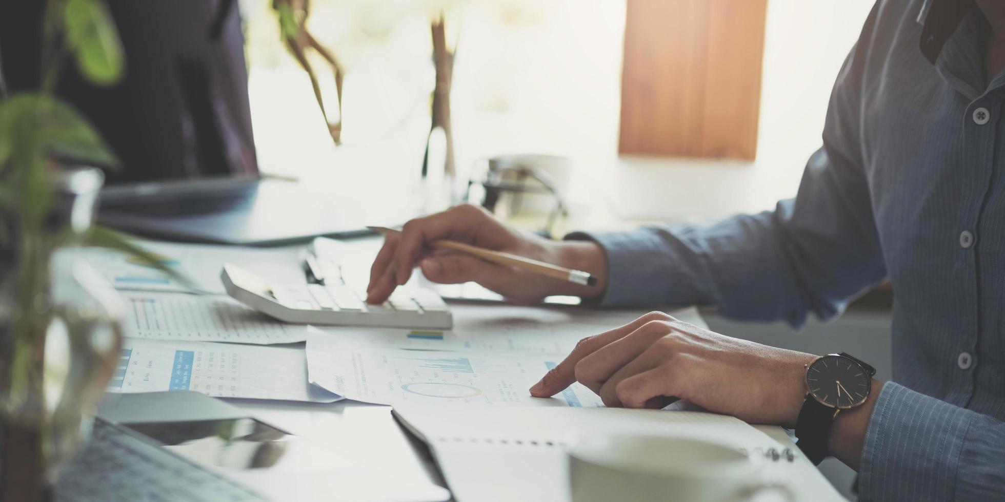 Close up Business woman using calculator and laptop for do math finance on wooden desk in office and business working background, tax, accounting, statistics and analytic research concept photo