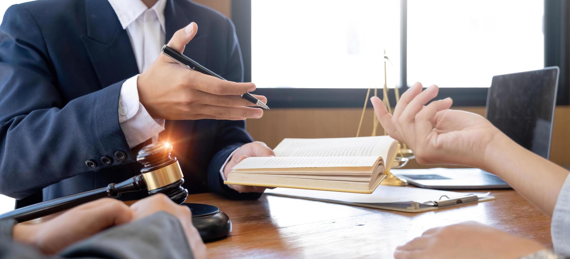 Lawyer hands holding a legal book and clarify the law to client while sign a contract at lawyer office photo