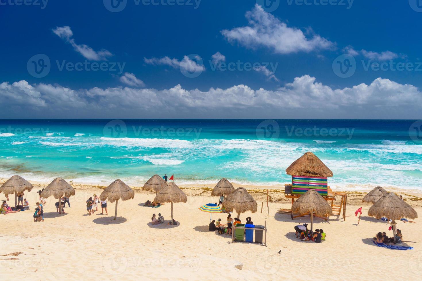 Umbrelas on a sandy beach with azure water on a sunny day near Cancun, Mexico photo