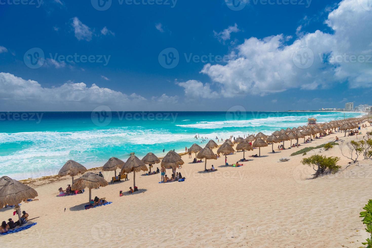 Umbrelas on a sandy beach with azure water on a sunny day near Cancun, Mexico photo