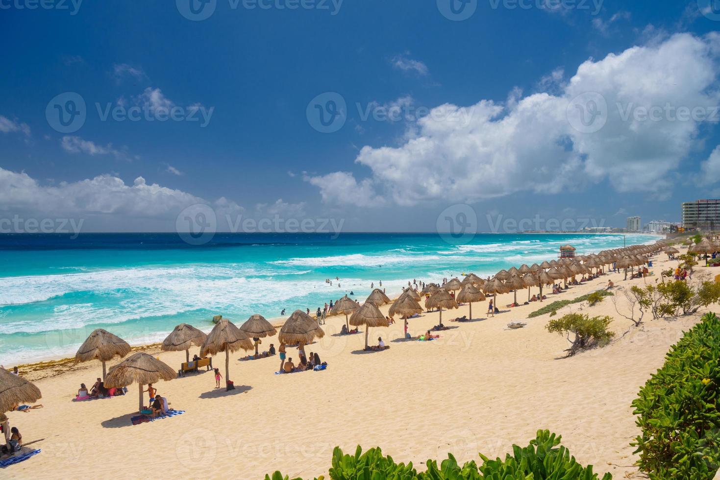 Umbrelas on a sandy beach with azure water on a sunny day near Cancun, Mexico photo